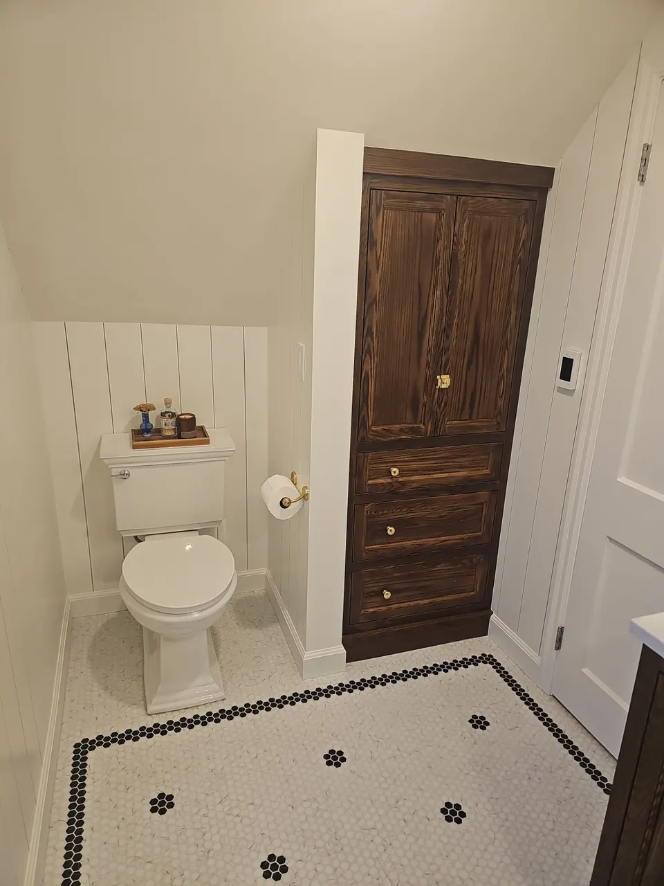 Bathroom with tile wainscot and a dark painted door