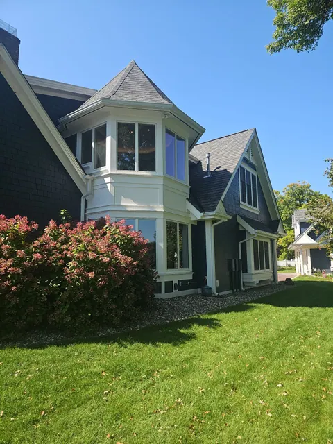 Navy painted shake siding on a turret with crisp white trim, photographed from the yard.