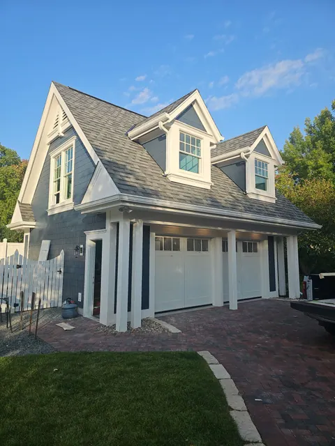 Small white painted house with blue shutters and white trim, photographed from the street.
