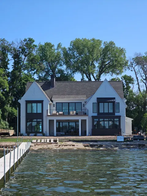 Modern farmhouse style home with white painted siding and dark trim on a lakeshore lot, exterior freshly painted.