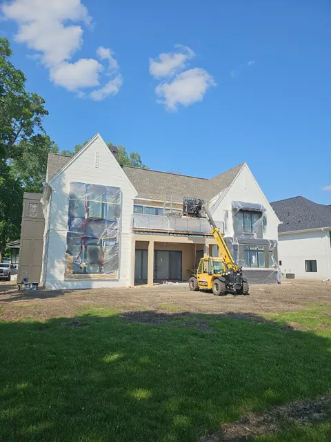Newly built two-story home with white painted siding and fresh trim, bare yard not yet graded.