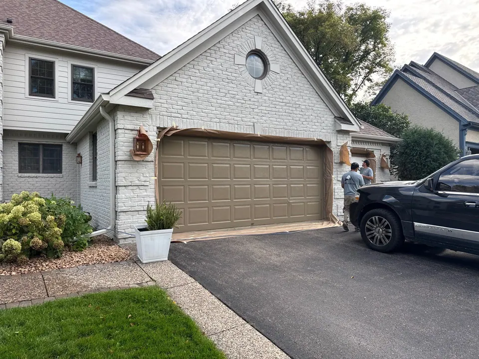 Attached garage with painted siding and brick accent